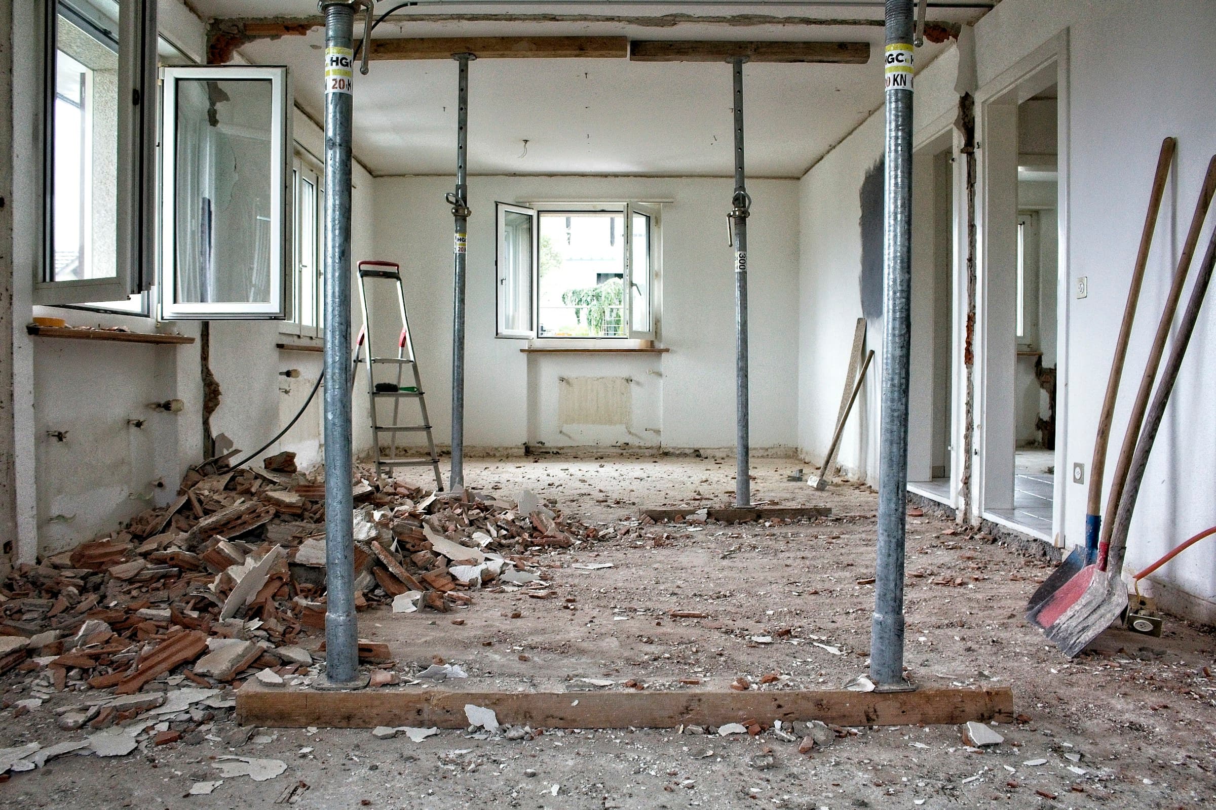A room stripped back mid-renovation, props holding the ceiling and tools on the floor.